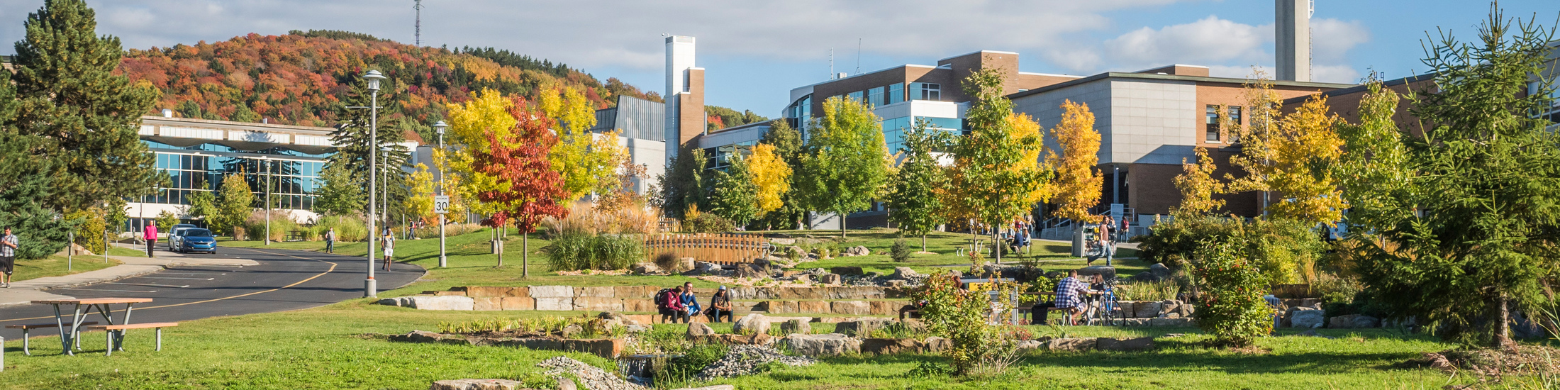 Campus de l'Université de Sherbrooke en automne avec étudiants et paysage montagneux de l'Estrie en arrière-plan