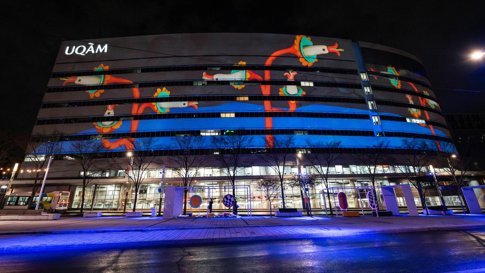 Façade artistique illuminée de l'UQAM au centre-ville de Montréal avec projection colorée nocturne créative